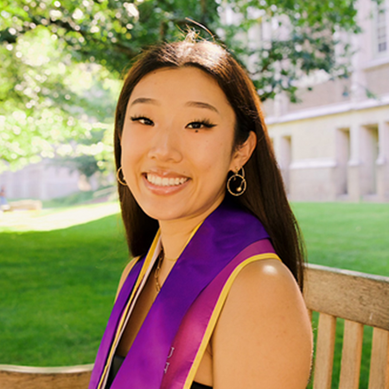 A smiling person with long, brown hair posing outside